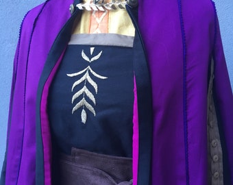 May include: A purple and black costume with a brown belt and a gold leaf design on the chest. The costume has a long cape with a pink lining.