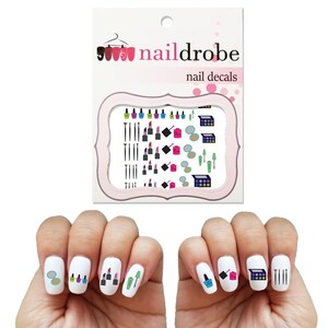 Könnte beinhalten: Nagelaufkleber mit Make-up-Motiven. Die Folie enthält Bilder von Lippenstiften, Nagellackflaschen, Lidschattenpaletten und Make-up-Pinseln. Die Folie ist mit "nailerobe nail decals" beschriftet.