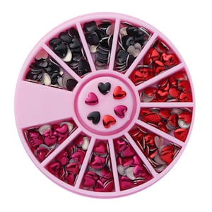 Könnte beinhalten: Ein rosa Plastikrad mit 12 Fächern, gefüllt mit kleinen roten und schwarzen herzförmigen Strasssteinen.