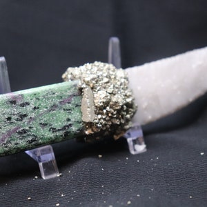Puede incluir: Un cuchillo de piedra zultanita verde y negro con un mango de racimo de cristal de pirita plateada y una hoja de cuarzo blanco.