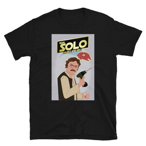 May include: Black t-shirt featuring a graphic of Ron Swanson from the TV show Parks and Recreation dressed as Han Solo from Star Wars. The graphic reads "Ron Solo Parks and Rec".