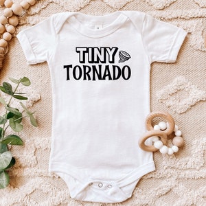 May include: White baby onesie with black text that reads "Tiny Tornado" and a small black tornado graphic.