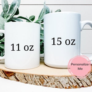 K&ouml;nnte beinhalten: Zwei wei&szlig;e Keramikbecher mit schwarzem Text. Der Becher links zeigt "11 oz" und der Becher rechts zeigt "15 oz".