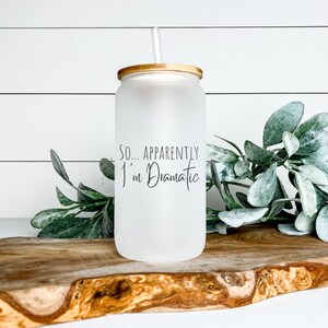 Könnte beinhalten: Ein mattierter Glasbecher mit Bambusdeckel und Strohhalm. Auf dem Becher steht der Text "SO... APPARENTLY I'm Dramatic".