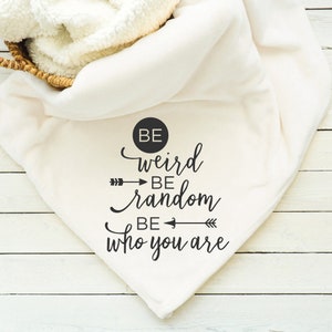 May include: White throw blanket with black text that reads "Be weird be random be who you are".