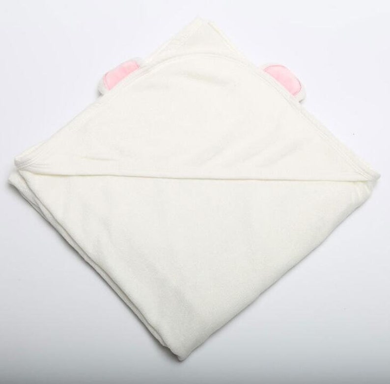 Op de afbeelding: Witte badcape met roze berenoren. De badcape is dubbelgevouwen en gemaakt van zacht, absorberend materiaal.