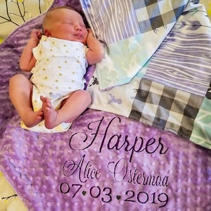 May include: Purple baby blanket with a white and gray patchwork design. The blanket has the name "Harper Alice Ostermaa" and the date "07.03.2019" embroidered on it.