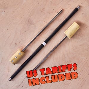 May include: Two fire spinning staffs with metallic shafts and yellow wick heads. One staff features a black grip with a white band, while the other is plain metal. The text US TARIFFS INCLUDED is printed in orange with a black outline at the bottom.
