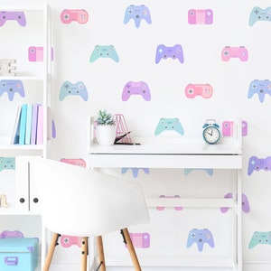 May include: A white desk with a white chair in front of it. The wall behind the desk is decorated with pastel-colored game controller stickers. There is a small alarm clock on the desk.