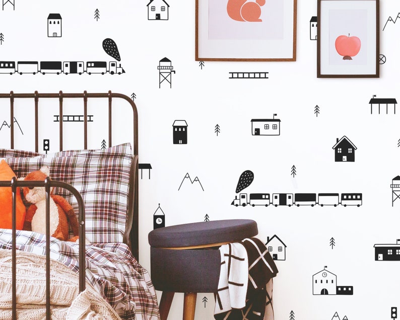 May include: Black and white wall decals featuring a train, houses, trees, and mountains. The decals are on a white wall in a child's bedroom.