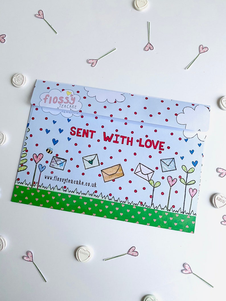 May include: A blue and white envelope with red polka dots and a green border. The envelope has a drawing of flowers, bees, and envelopes with the text "Flossy Teacake" and "Sent with Love" on it. The website address "www.flossyteacake.co.uk" is printed on the envelope.
