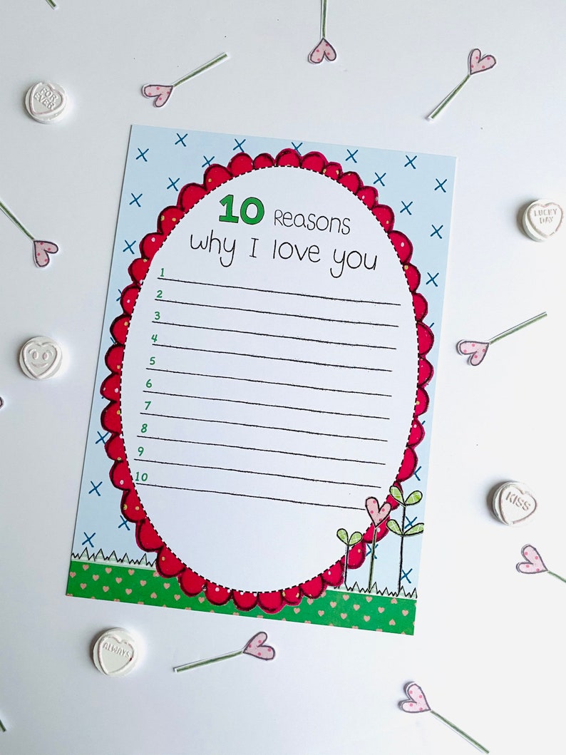 May include: A printable card with a red heart-shaped frame and the text "10 Reasons why I love you" with lines for writing. The card has a green grass border and a blue background with white X's.