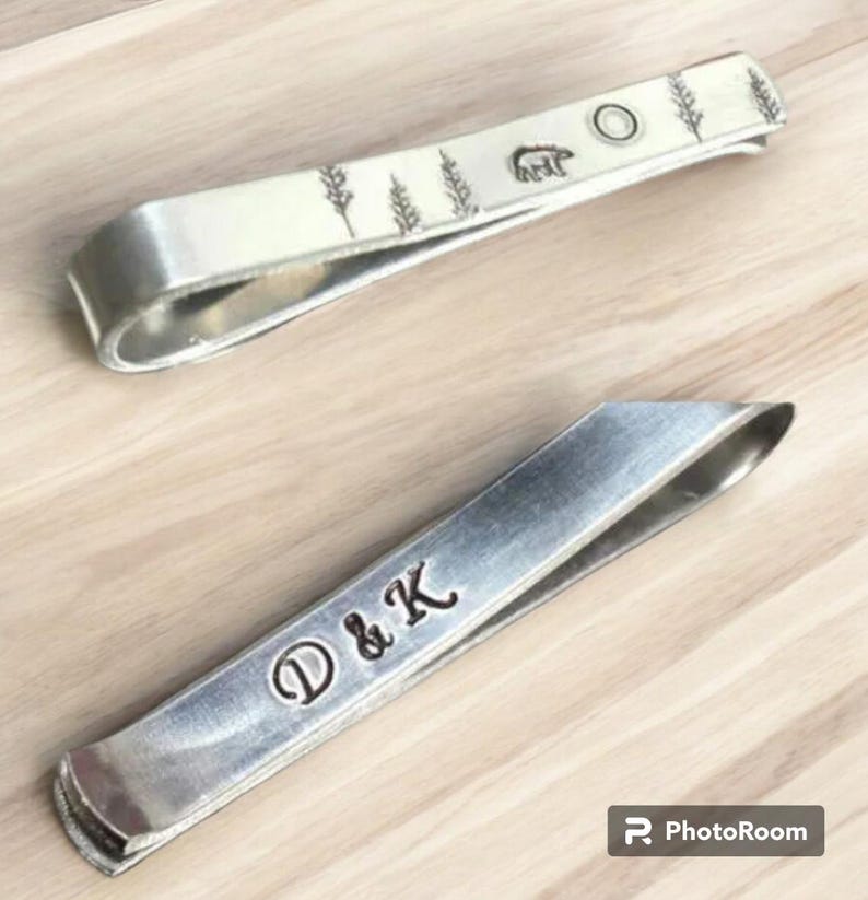 May include: Two silver tie clips. One has a design of trees and a bear with the text "D & K" engraved on the other.