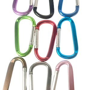 May include: Assortment of ten colorful metal carabiner clips. The clips are in various colors, including purple, black, blue, green, red, silver, and brown.