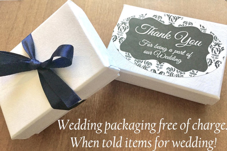 K&ouml;nnte beinhalten: Zwei wei&szlig;e Geschenkboxen, eine davon mit einem dunkelblauen Band. Die Box rechts hat einen Aufkleber mit der Aufschrift "Vielen Dank, dass Sie Teil unserer Hochzeit waren".