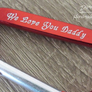 May include: Red metal carabiner keychain with a silver ring and the inscription "We Love You Daddy".
