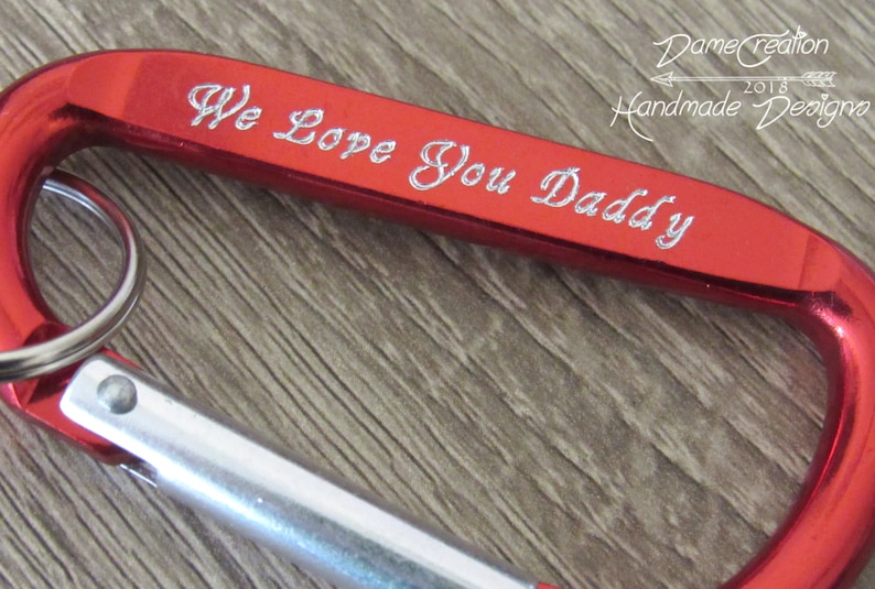 May include: Red metal carabiner keychain with a silver ring and the inscription "We Love You Daddy".