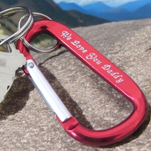 May include: Red metal carabiner keychain with a silver loop and the inscription "We Love You Daddy".