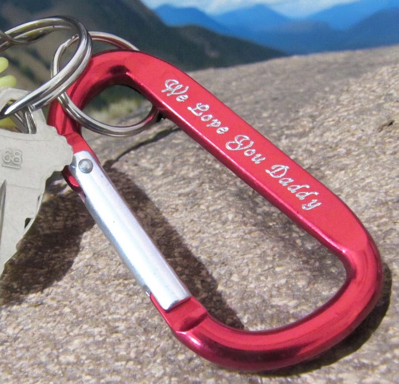 May include: Red metal carabiner keychain with a silver loop and the inscription "We Love You Daddy".