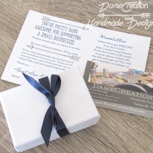 Peut inclure: Une bo&icirc;te cadeau blanche nou&eacute;e d'un ruban bleu marine. La bo&icirc;te est pos&eacute;e sur une surface en bois. Une carte blanche avec du texte noir indique "You're pretty darn awesome for supporting a small business!!!" et "Please remember to leave a review @www.DameCreation.Etsy.com". Une carte blanche avec du texte noir indique "DameCreation 2018 Handmade Designs Newsletter Subscribers get 20% OFF Your Next Order: http://eepurl.com/cDnu3n If you don't have a QR reader on your phone simply add the link and sign-up! You will get a monthly newsletter of". Une carte de visite blanche avec du texte noir indique "DAMECREATION Ann Kowalski Jewelry Designer, Shop Owner akowalski@gmail.com www.DameCreation.Etsy.com Handmade Designs Taylorsville, NC".