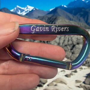 May include: A rainbow-colored metal carabiner with the name "Gavin Rivers" engraved on it.
