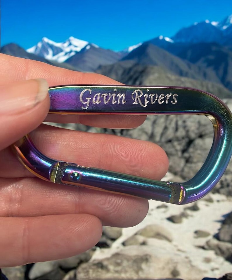 May include: A rainbow-colored metal carabiner with the name "Gavin Rivers" engraved on it.
