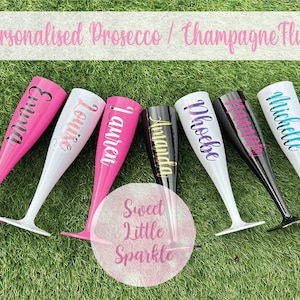 May include: A selection of seven personalised champagne flutes in pink, white, and black, each bearing a different name. The text "Personalised Prosecco / Champagne Flutes" is displayed above the flutes.