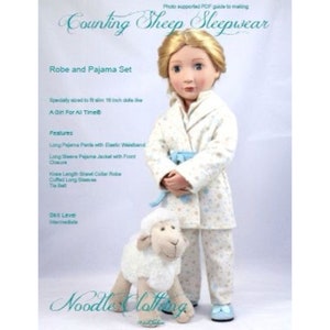 May include: A white robe and pajama set with a blue and white sheep print for a 18 inch doll. The set includes a long-sleeved pajama jacket with a front closure, long pajama pants with an elastic waistband, a knee-length shawl collar robe with cuffed long sleeves, and a tie belt. The doll is wearing the set and holding a white stuffed sheep.