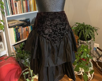 May include: A black skirt with a ruffled hem and a velvet waistband with a paisley pattern.