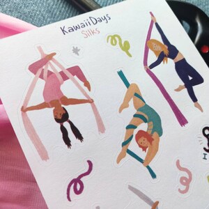 Pode incluir: Uma folha de adesivos com ilustra&ccedil;&otilde;es de pessoas realizando acrobacias a&eacute;reas em tecidos. Os adesivos est&atilde;o em um fundo branco e apresentam o texto "Kawaii Days Silks".