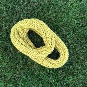 May include: A yellow knitted infinity scarf. The scarf is made of a soft, chunky yarn and is perfect for keeping warm in the winter.