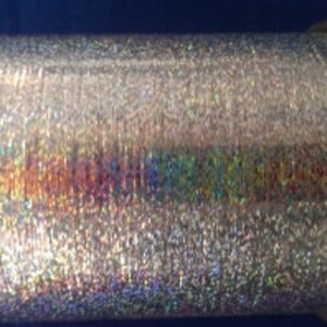 May include: A spool of silver iridescent metallic thread. The thread is shiny and has a holographic effect.