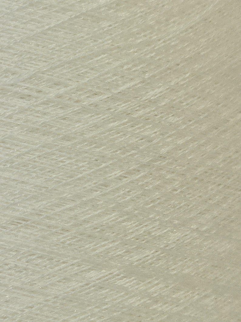 May include: A close-up of a spool of white yarn with a subtle shimmer.