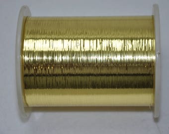 May include: A spool of gold metallic thread, wound tightly on a clear plastic bobbin.