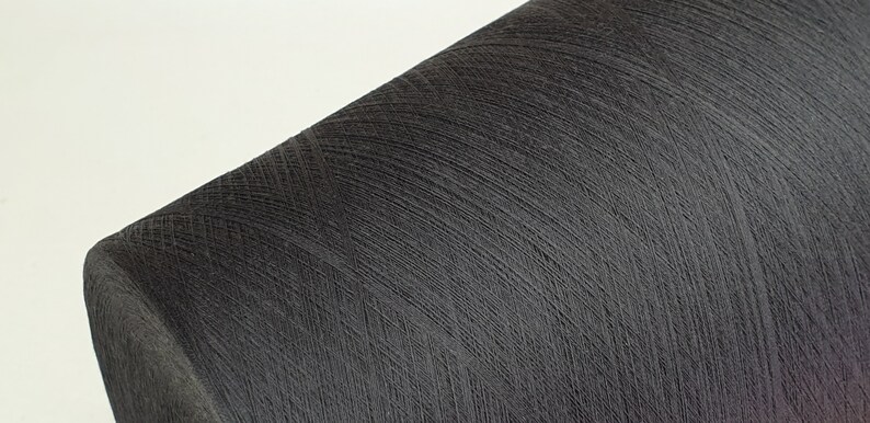 May include: A close-up of a spool of black thread.