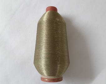 May include: A spool of gold metallic thread with a red plastic top.