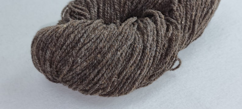 May include: A skein of dark brown yarn, likely wool, with a slightly textured surface.