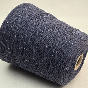 Peut inclure: Une pelote de fil bleu foncé avec des reflets rouges et blancs. Le fil est enroulé en forme de cône.