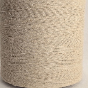 May include: A spool of natural beige jute twine. The twine is wound tightly around the spool and has a slightly rough texture.