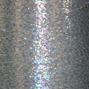 May include: Close-up of a silver metallic spool of thread with a shimmering iridescent sheen.
