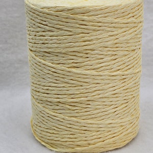 Peut inclure: Une bobine de cordon en papier jaune pâle. Le cordon est enroulé serré et a une texture naturelle légèrement rugueuse.