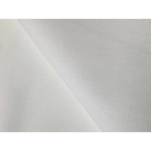 Può includere: Tessuto bianco con una texture liscia e uniforme. Il tessuto è piegato a metà, mostrando i lati anteriore e posteriore.