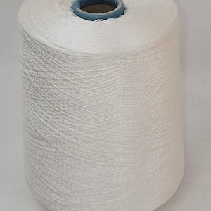 May include: A white spool of thread wound tightly on a cardboard core. The thread is smooth and appears to be made of natural fibers.