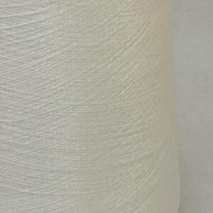 May include: A close-up of a white spool of thread.