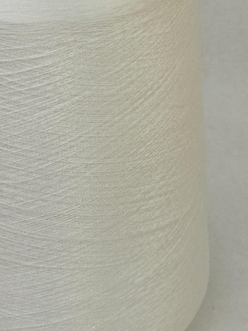 May include: A close-up of a white spool of thread.