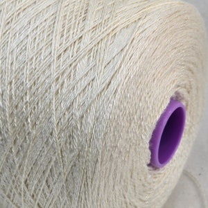 Può includere: Un'bobina di filo color crema con un centro in plastica viola.