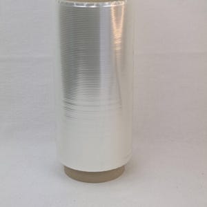 Può includere: Un rotolo di pellicola trasparente per alimenti su un nucleo di cartone. La pellicola è progettata per la conservazione degli alimenti ed è comunemente usata nelle cucine.