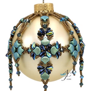 May include: A beaded Christmas ornament with a gold base and a teal and blue design. The ornament features a cross-shaped pattern with dangling beads.