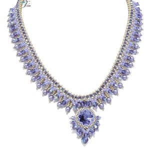 Puede incluir: Un delicado collar de cuentas plateadas y lavanda con un gran colgante de cristal morado facetado.