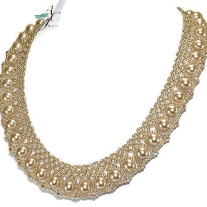 May include: A gold-colored beaded necklace with large, round, faux pearls. The necklace has a woven design with the pearls evenly spaced along the front. The necklace is on a white background.